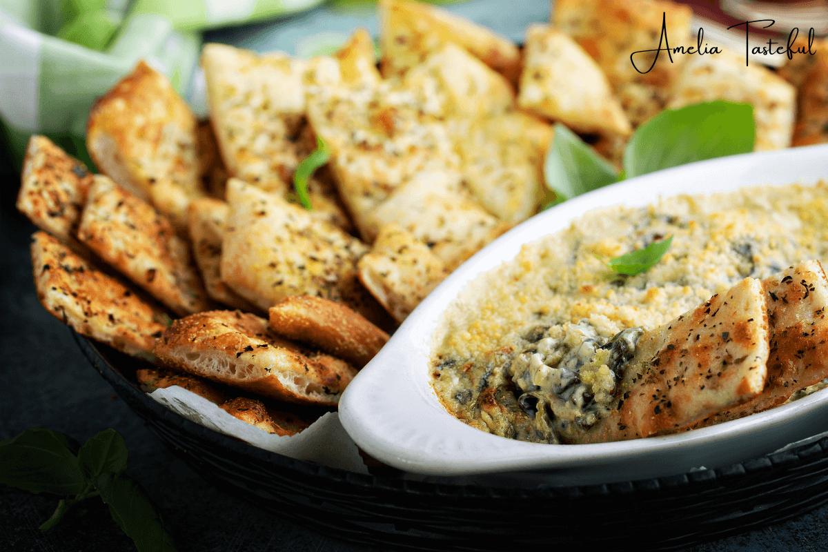 A bowl of creamy spinach dip surrounded by fresh vegetables and crackers.